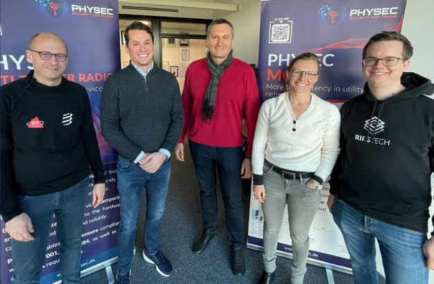 PHYSEC CEO Christian Zenger gemeinsam mit Olivier Gaudin, Mario Patov, Christel Warin und Fabian Langen von SonaSource vor PHYSEC Banner