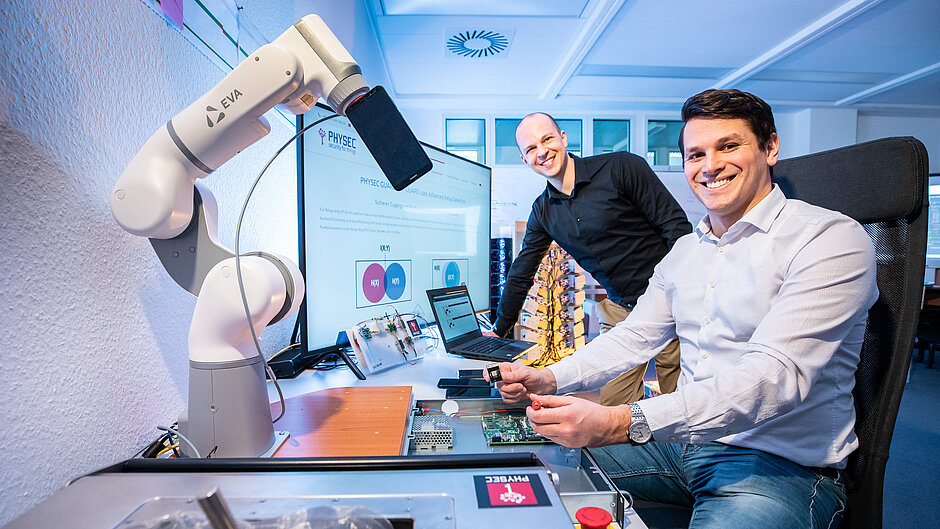 Die zwei Gründer von PHYSEC Christian Zenger und Heiko Koepke neben einem Roboter