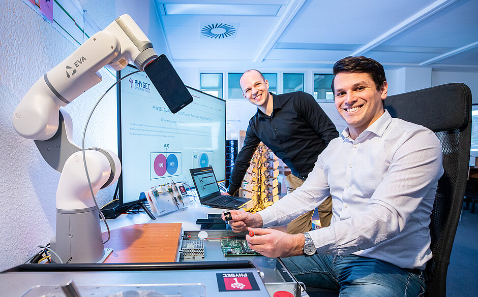 Die zwei Gründer von PHYSEC Christian Zenger und Heiko Koepke vor einem Roboter