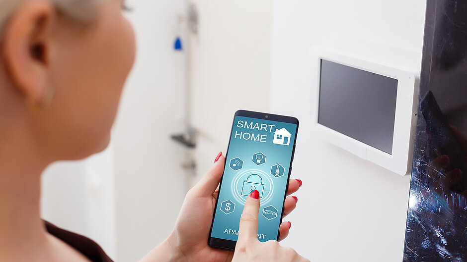 Woman with a smartphone on which a smart home app is open