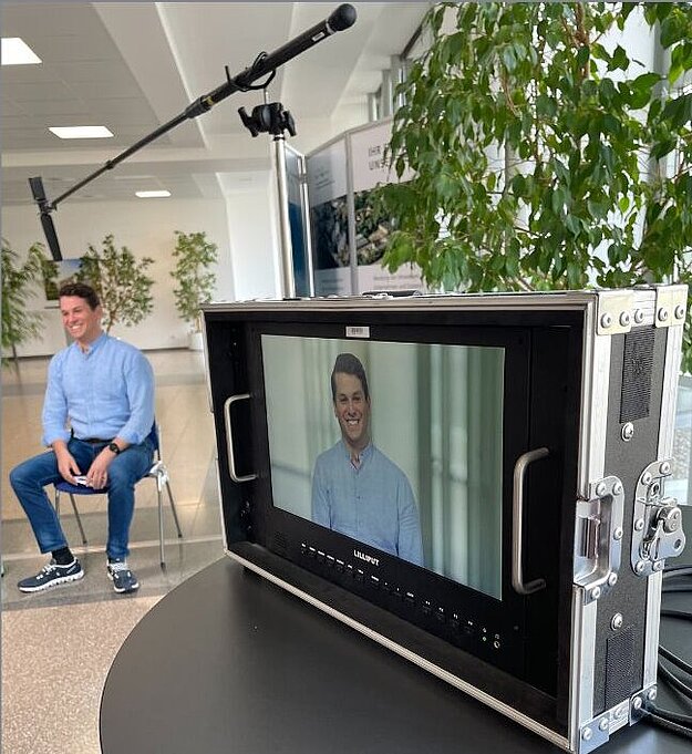 CEO Christian Zenger in Büro und auf einem Kamerabildschirm 