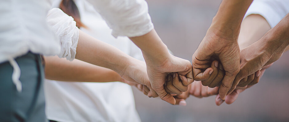 Four pairs of employees' hands forming a circle with their fists